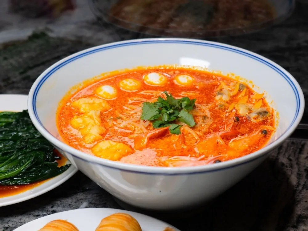 A bowl of Thai red curry soup with shrimp, garnished with fresh coriander